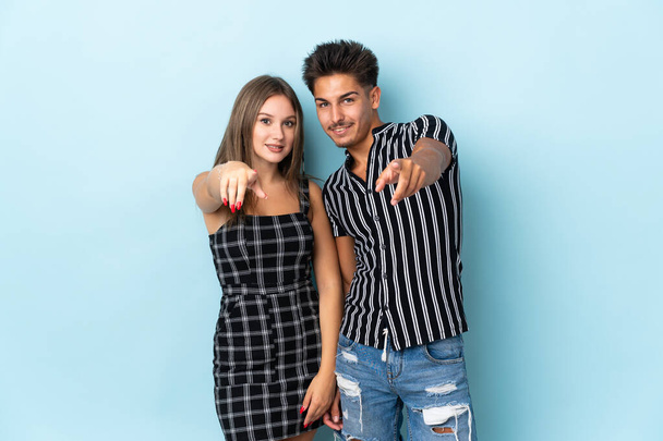 Teenager caucasian couple isolated on blue background points finger at you with a confident expression - Fotó, kép
