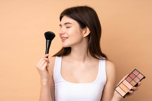 Young Ukrainian teenager girl over isolated background with makeup palette and happy - Photo, Image