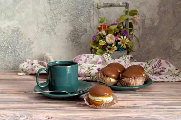 Bir tabakta üç taze, lezzetli kek ve ahşap arka planda bir fincan çay. - Fotoğraf, Görsel