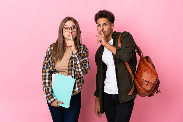 Young student couple isolated on white background showing a sign of silence gesture putting finger in mouth - Photo, Image