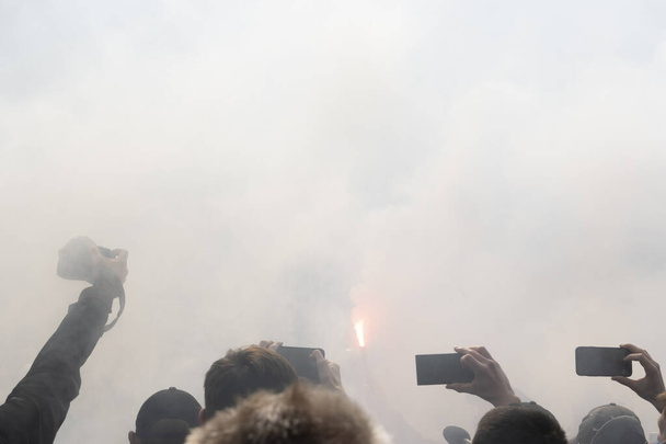 Ludzie strzelają do protestów ulicznych przez telefon i kamerę. fotografowie trzymają telefony i kamery w białym dymie podczas masowych protestów - Zdjęcie, obraz