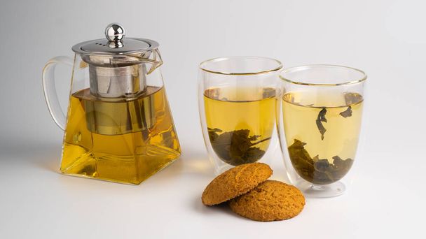 Hojas de té en una olla transparente y galletas de avena como concepto de desayuno - Foto, Imagen