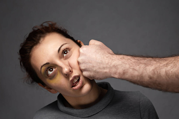 Bir erkeğin yumruğu bir kadının yüzüne vurur. Aile içi çatışma ve şiddet. - Fotoğraf, Görsel