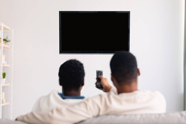 Czarna para ogląda TV z makietą i za pomocą pilota - Zdjęcie, obraz