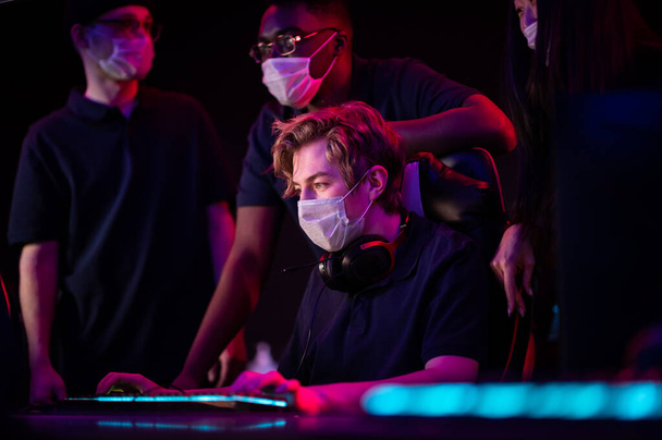 Jovens com máscaras médicas jogam em um clube de informática durante a pandemia do covid-19 - Foto, Imagem