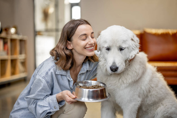 Kobieta karmiąca psa suchym jedzeniem w domu - Zdjęcie, obraz