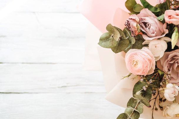 a large and beautiful bouquet of fresh roses, eustoma, matiola, freesia, eucalyptus, hydrangea in delicate pink and white colors, on a white wooden background in the style of Provence. Copy space. - Foto, Imagem