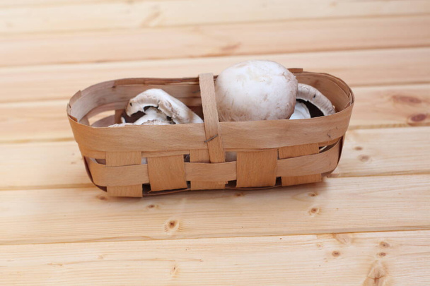 cogumelos frescos em uma cesta de vime em um soalho de madeira. - Foto, Imagem