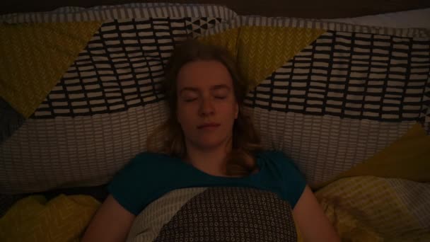 夜から昼への光の変化としてベッドの中でブロンドの女性のオーバーヘッドショットと目覚め - 映像、動画