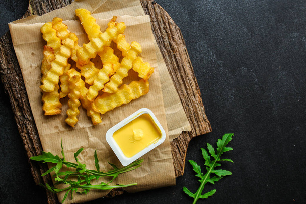 Хрустящие картофельные чипсы с кетчупом и петрушкой на деревянном фоне - Фото, изображение