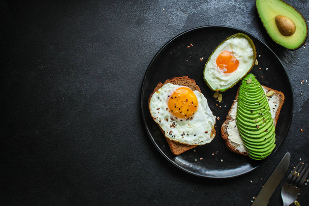 top view of fried eggs with avocado on a black background. top view. - Foto, Bild