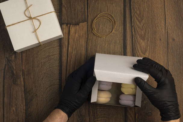 Les mains en gants noirs emballent les guimauves en boîte dans le service de livraison de nourriture - Photo, image