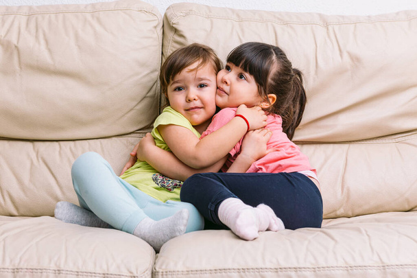 Δύο κορίτσια αδελφή αγκάλιασε, ξαπλωμένη σε έναν καναπέ παίζοντας - Φωτογραφία, εικόνα