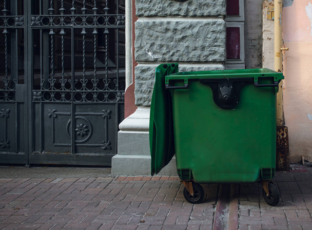 contenedor de basura verde en la calle. contenedor de basura cerca de la casa. viejo cubo de basura sin clasificación. - Foto, imagen