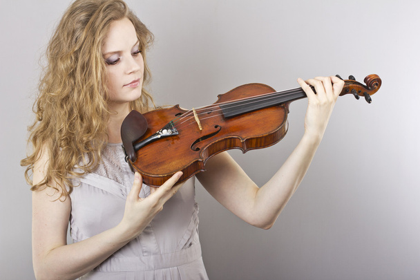 Beautiful curly blonde in gray evening dress with red violin in her hands - Foto, Bild