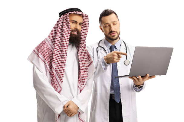 Serious doctor showing a laptop computer to a saudi arab man isolated on white background - Фото, изображение