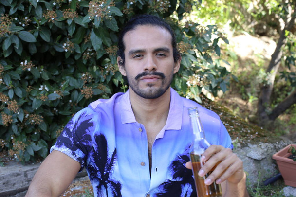 portrét pohledného mladého muže ve stylové purpurové košili s lahví piva venku - Fotografie, Obrázek