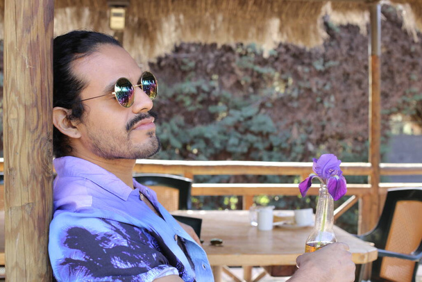 портрет красивого молодого чоловіка в стильній фіолетовій сорочці з орхідеєю на відкритому повітрі
 - Фото, зображення