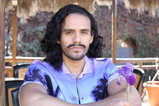 Porträt eines hübschen jungen Mannes in stylischem lila Hemd mit Orchideenblume im Freien - Foto, Bild