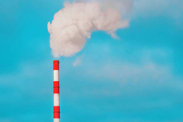 Milieuverontreiniging, milieuprobleem, rook uit de pijp van een industriële installatie of thermische centrale tegen een blauwe lucht. - Foto, afbeelding