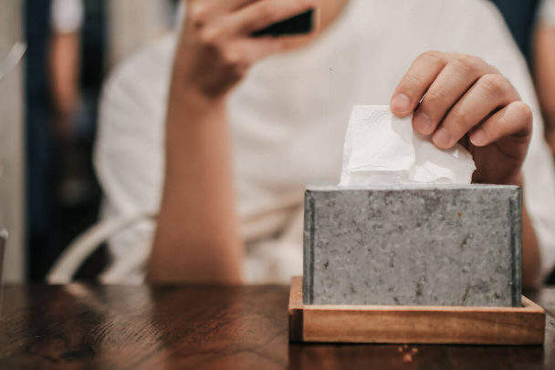 Man taking paper tissue from holder in restaurant. Caffe or restaurant on background. - Photo, Image