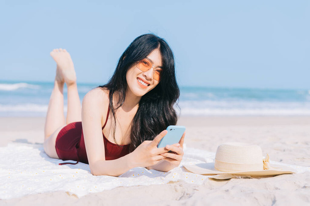 Kaunis nuori aasialainen nainen uimapuvuissa rentouttava rannalla kesäloman aikana - Valokuva, kuva