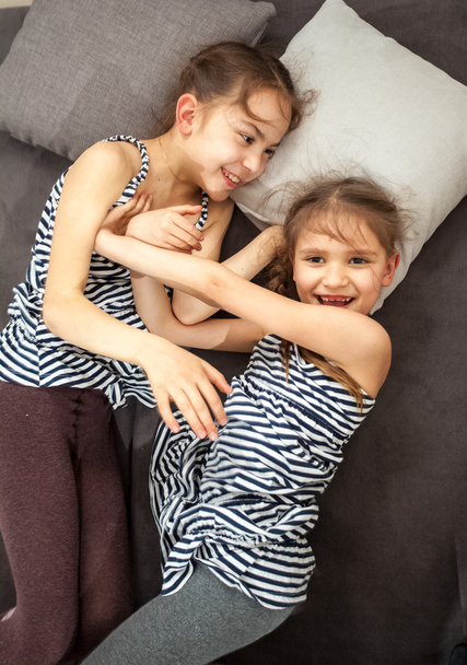 two young sisters pushing each other on bed - Фото, зображення