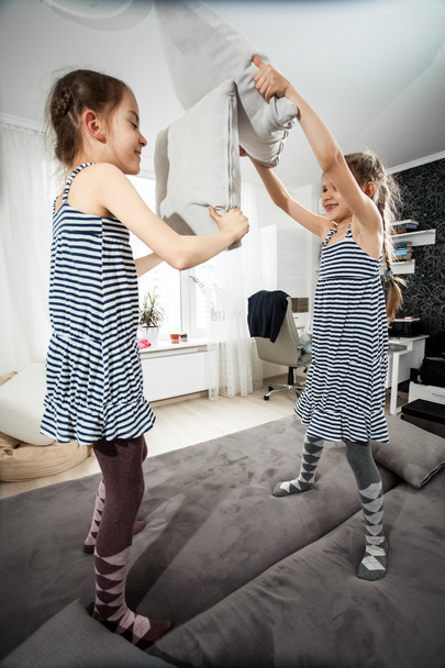 children having fight with pillows on bed - Foto, imagen