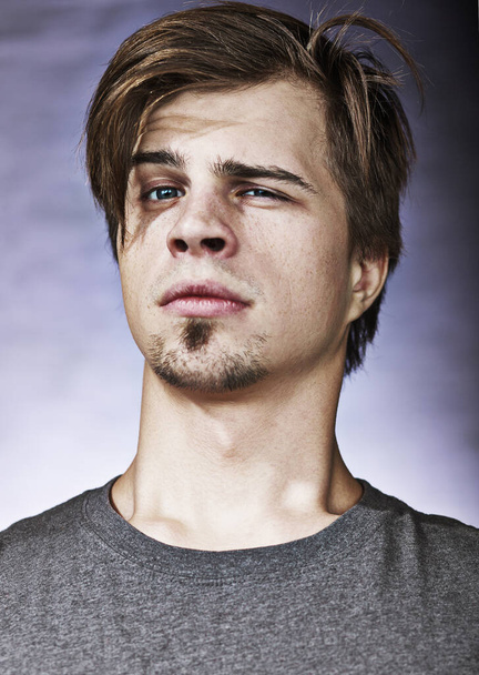 Studio portrait of a confident arrogant young man with a cross-eyed eyes in a gray T-shirt on a lilac background - Photo, Image