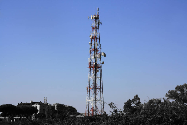 Vista da cidade rural em preto e branco. Céu azul e torre de telecomunicações colorida. Transmissor de antena para comunicação sem fio: 3G, 4G, 5G - Foto, Imagem