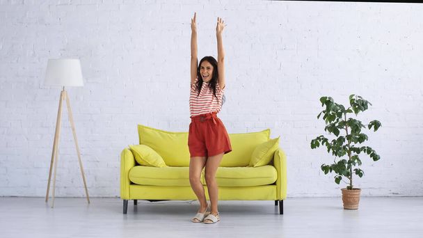 happy woman dancing near sofa in modern living room - Foto, Imagem