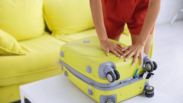 частковий вид на жінку, що спирається на жовту сумку подорожі біля дивана у вітальні
  - Фото, зображення