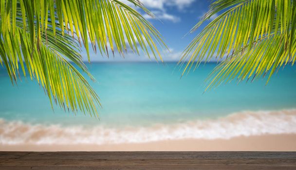 Dřevěný stůl a palmové listy před rozmazané tropické moře pozadí. - Fotografie, Obrázek