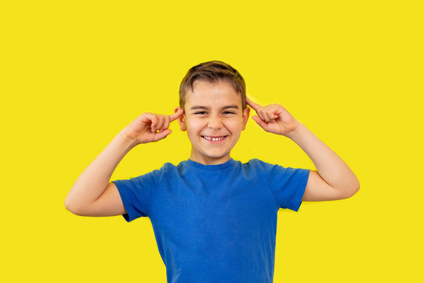 niño de 6 años en camiseta azul sobre fondo amarillo, expresión de emoción divertida tonta en la cara - Foto, Imagen