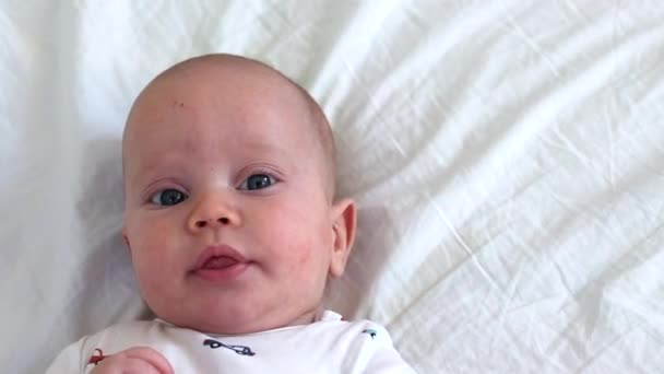 Nahaufnahme eines Babys, das auf einem weißen Laken liegt und Arme bewegt, die nach oben schauen - Filmmaterial, Video
