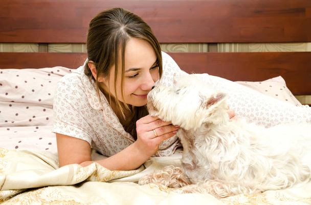 nő pizsamában és kutya az ágyon - Fotó, kép