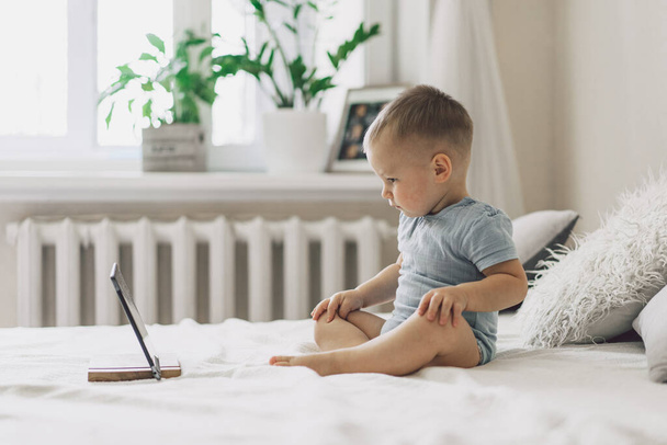 Little Boy sitting with a tablet in the room. The boy watching cartoons on the tablet. Technology concept. Child with a gadget - Foto, Bild