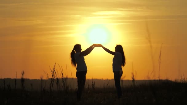 Meisjes hebben een prachtige zon in hun handen. Concept van familie, leven, warmte, hoop. Mam en dochter raakten hun handpalmen aan elkaar, overhandigden een prachtige zonsondergang. gelukkig familie mam en dochter - Video