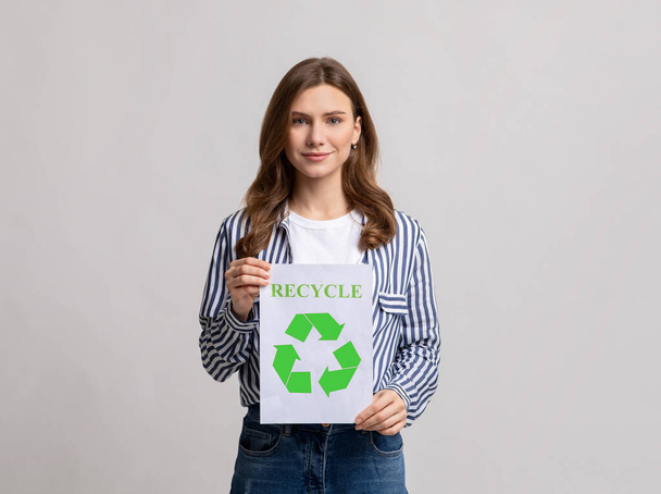 Milenial eco-activista dama mostrando placa con verde reciclar signo icono - Foto, imagen
