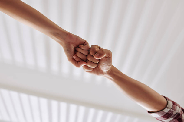 Hands of people making fist bump, view from below, teamwork and cooperation concept - Photo, Image
