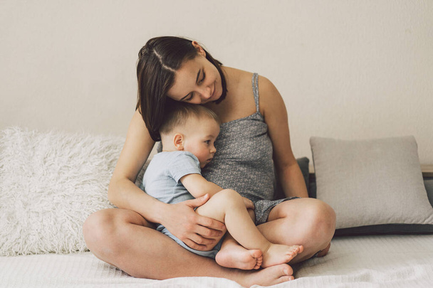 Young woman with her first child during second pregnancy. Motherhood and parenting concept. Toddler boy and mom. Happy family expecting for baby. - Valokuva, kuva