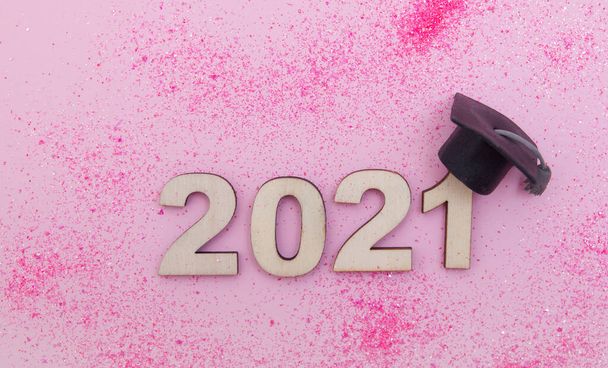 Promoce 2021: dřevěné číslo 2021 v graduační čepici na růžové třpytky pozadí horní pohled - Fotografie, Obrázek