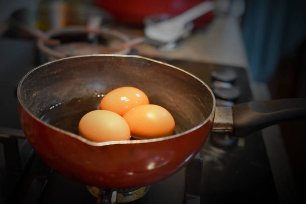 Яйца, кипящие в воде на газовой плите. - Фото, изображение