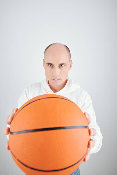 Egy jóképű, komoly, érett férfi portréja kosárlabdával a kezében és a kamerába nézve. - Fotó, kép