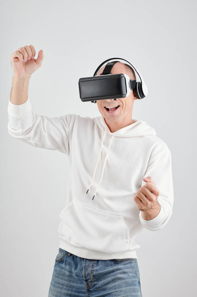 Retrato de hombre maduro emocionado feliz disfrutando jugando videojuego en auriculares de realidad virtual - Foto, imagen