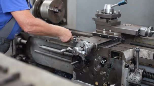 Prevenção e manutenção de máquinas-ferramentas na loja de máquinas. Um trabalhador em macacão configura um torno para trabalhar com metal - Filmagem, Vídeo