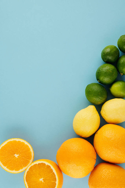 Agrumi agrodolci saporiti: arance, limoni e lime sulla tavola azzurra - Foto, immagini