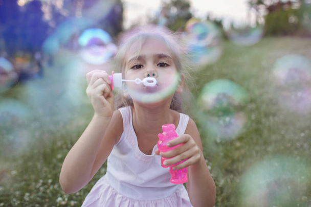 Девушка, пускающая мыльные пузыри в парке, счастливое детство, активные выходные на открытом воздухе летом - Фото, изображение