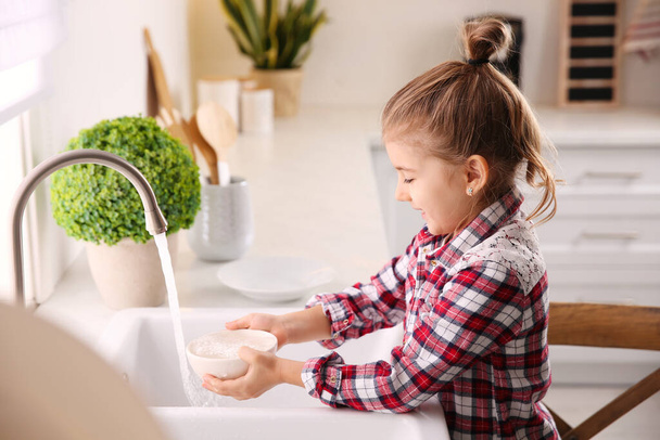 Little girl washing dishes in kitchen at home - Foto, Bild