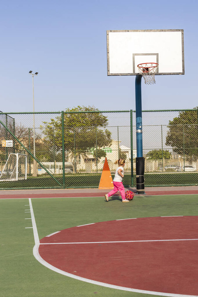 Petite fille jouant avec la balle sur le terrain de basket. - Photo, image